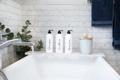 Alora matte white bottles with black script labels on shelves.