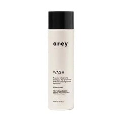 Arey Wash Shampoo bottle showcases a color-safe formula to help preserve pigment and promote strand health.