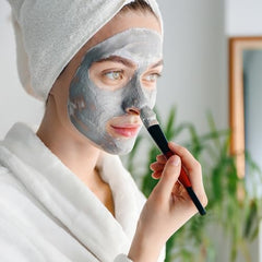 Mixing Bare Essentials Living Bentonite clay powder in a bowl for a DIY mask.