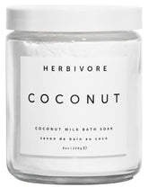 HERBIVORE Coconut Milk Bath Soak being poured into warm water for hydration.