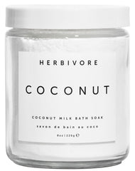 Herbivore Coconut Milk Bath Soak pouring into a warm bath for hydration and relaxation.