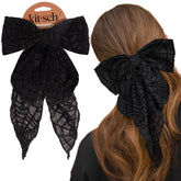 Kitsch black ribbon hair clip closeup showing bold bow for everyday outfits and party looks