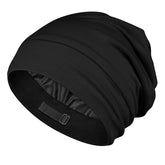 OLESILK silk baby bonnet in black on a sleeping baby, smoothing curls overnight.