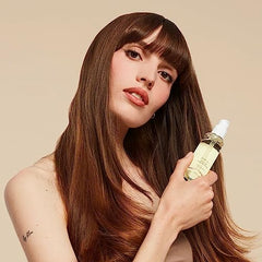 Hands applying OUAI Hair Oil for hydrating, heat-protective styling.