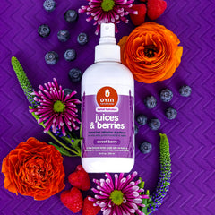 Bottle sits among natural oils, suggesting a nourishing scalp care routine with Oyin Handmade.