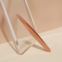 Tweezerman rose-gold tweezers used for brow shaping and fine-hair removal.