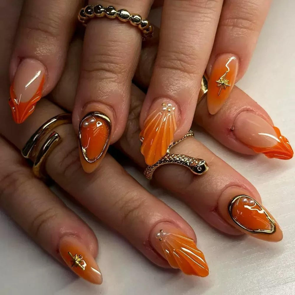 Yabonica orange almond press-on nails with gold lines for a glam salon look.