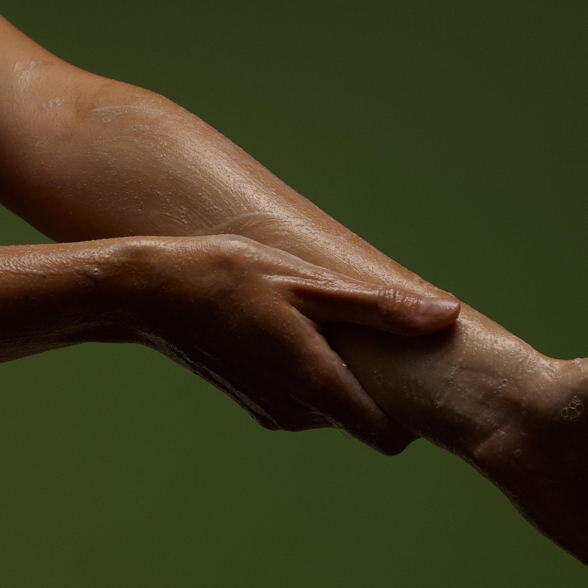 Aesop Geranium Leaf Exfoliating Body Scrub on damp skin illustrating massage-ready exfoliation.