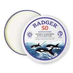 Badger reef-safe sunscreen tin on sunny beach for reef protection.