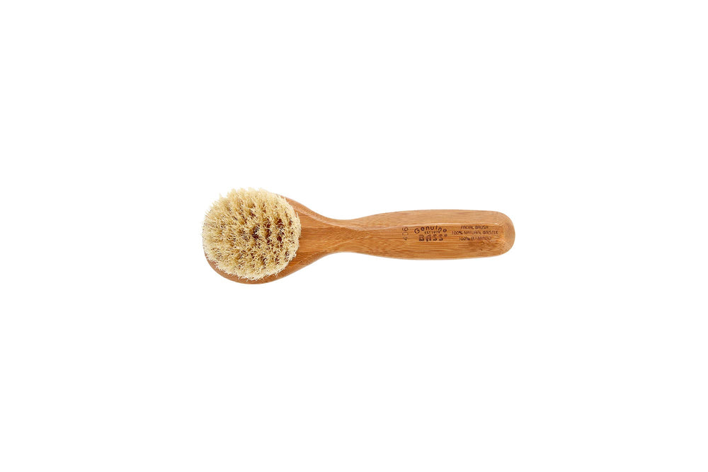 Bass Facial Cleansing Brush in hand demonstrating portable skin care tool.