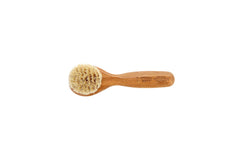 Bass Facial Cleansing Brush in hand demonstrating portable skin care tool.