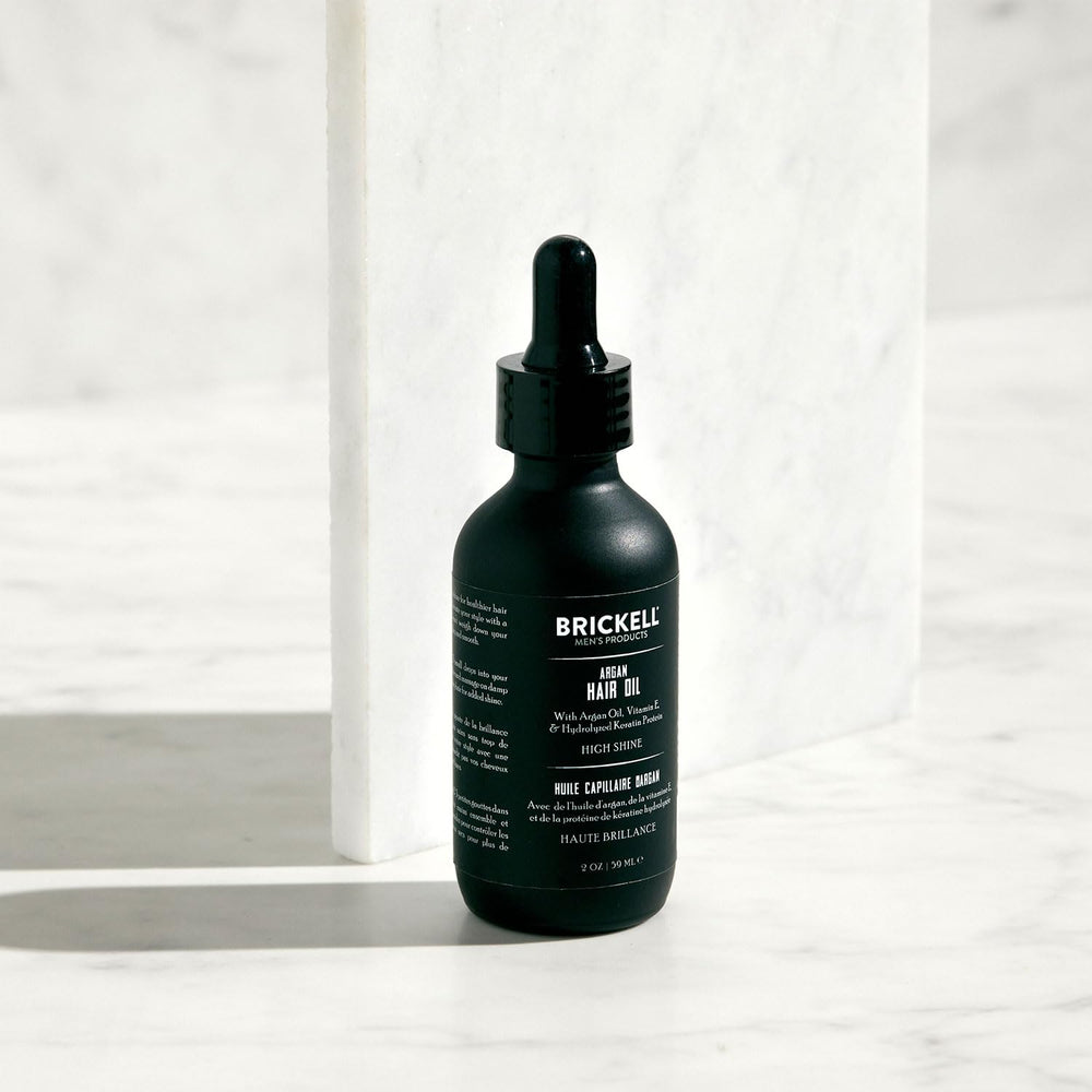 Hands applying Brickell Argan Oil for quick, light diffusion in daily grooming