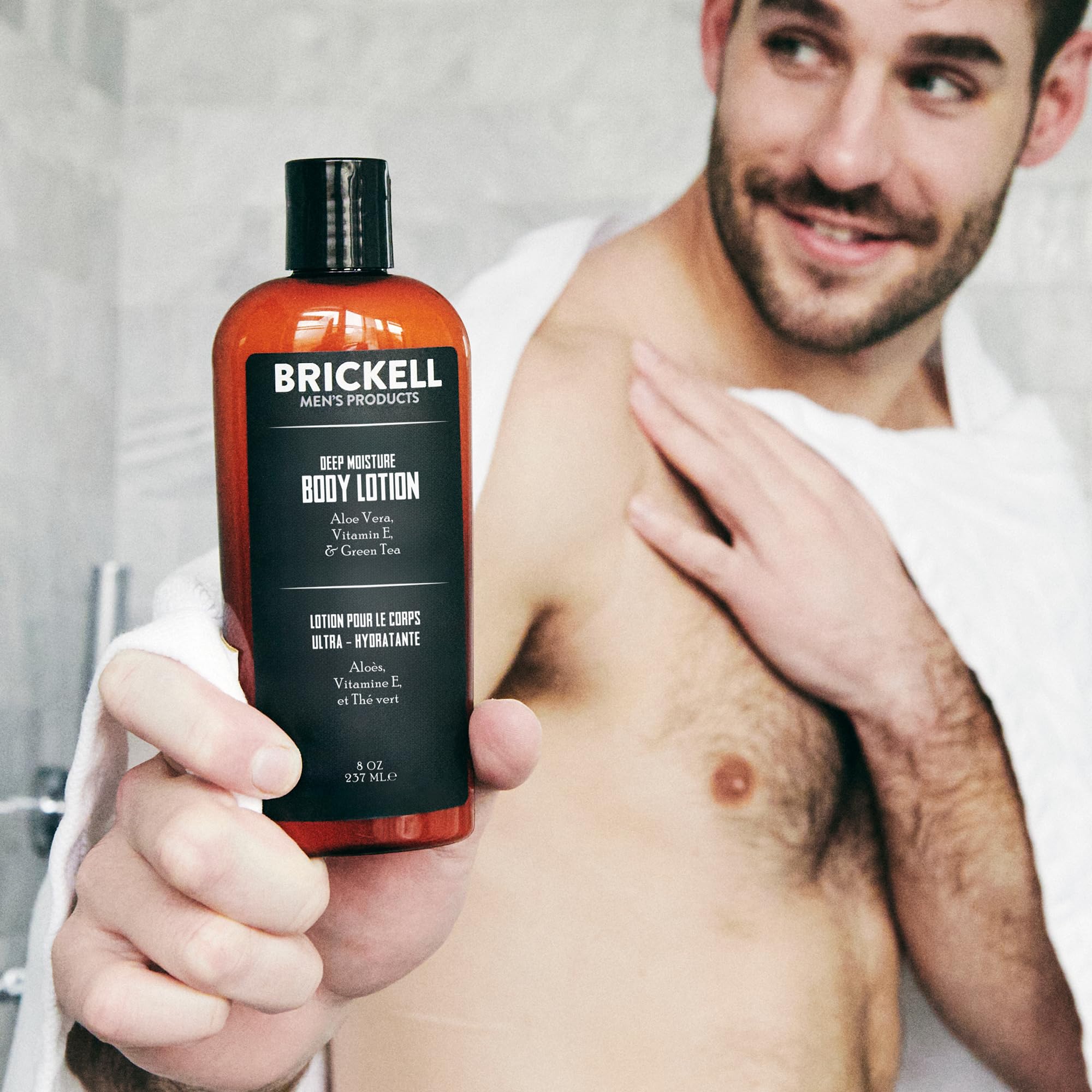 Applying Brickell Men's unscented lotion to arm for dry skin relief.