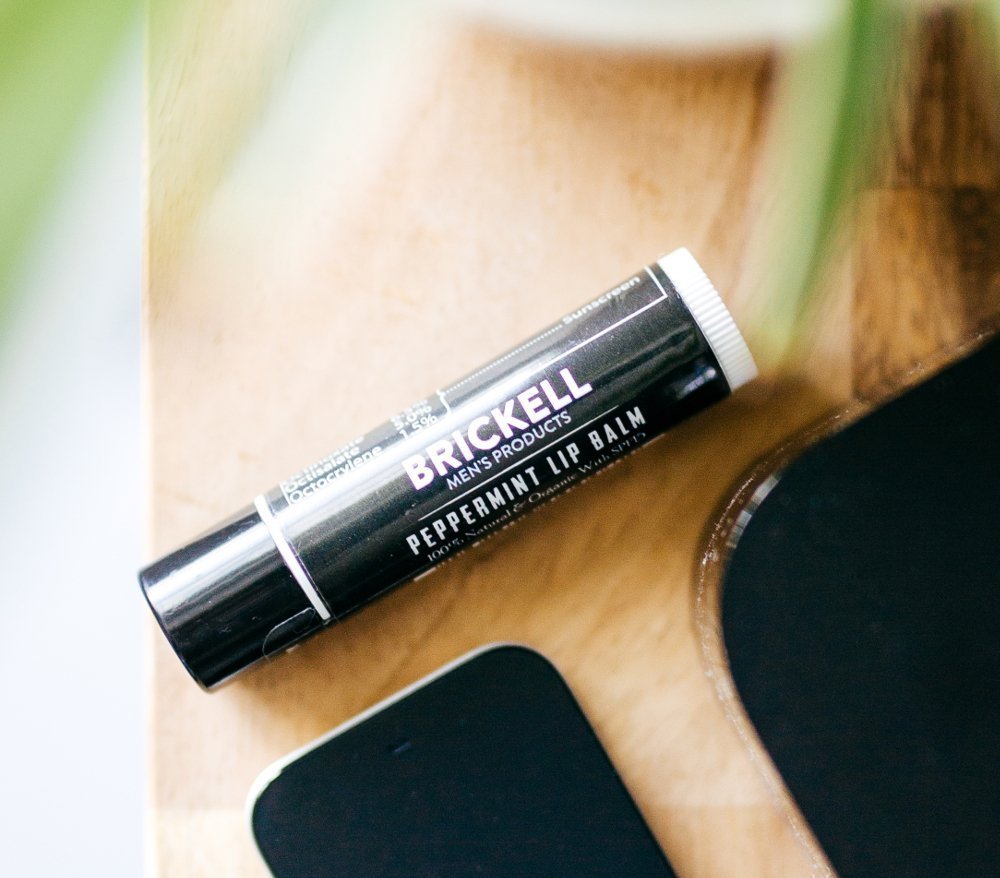 Brickell Men's No Shine Lip Balm being applied for daily moisture and protection.