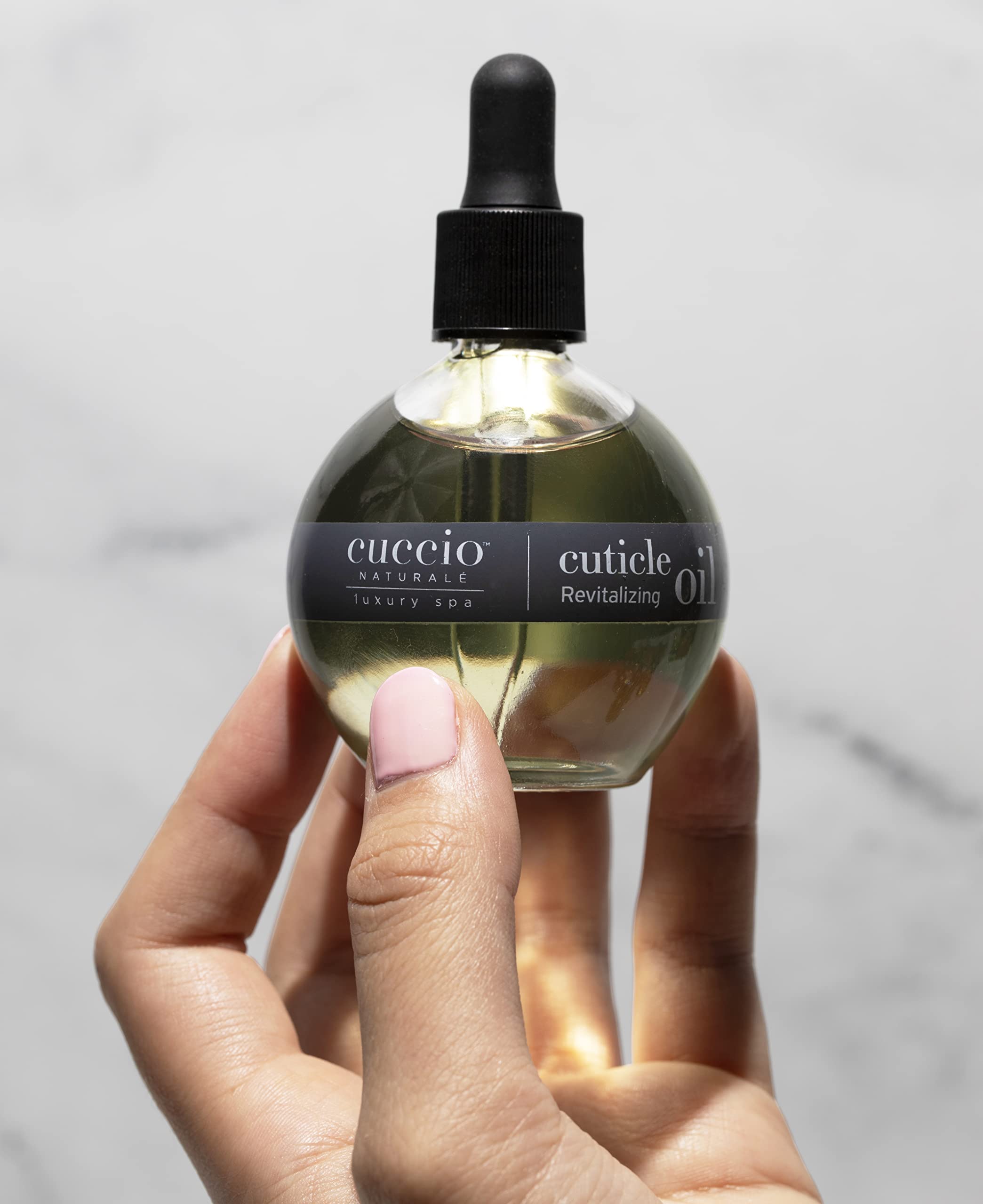 Cuccio Naturale Cuticle Oil Citrus Wild Berry bottle near nails showing quick absorption.