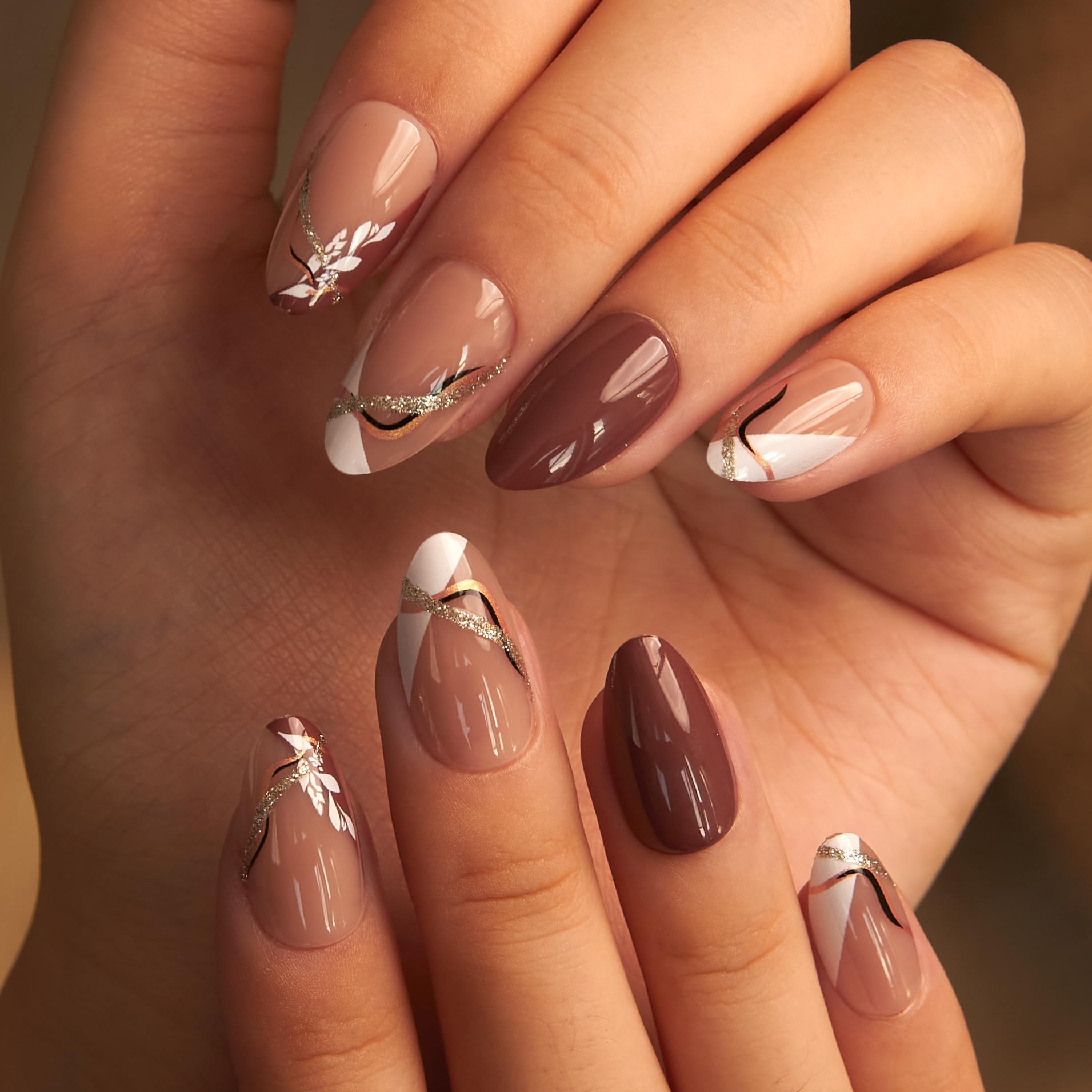 Curvlife nails feature golden line and leaf designs for an elegant look.