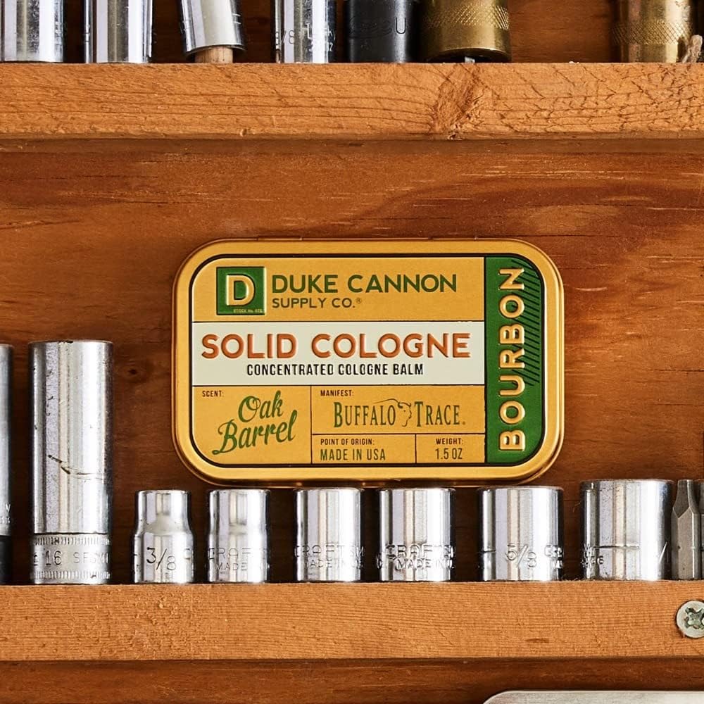 Duke Cannon Bourbon tin open for fingertip application of balm.