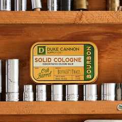 Duke Cannon Bourbon tin open for fingertip application of balm.
