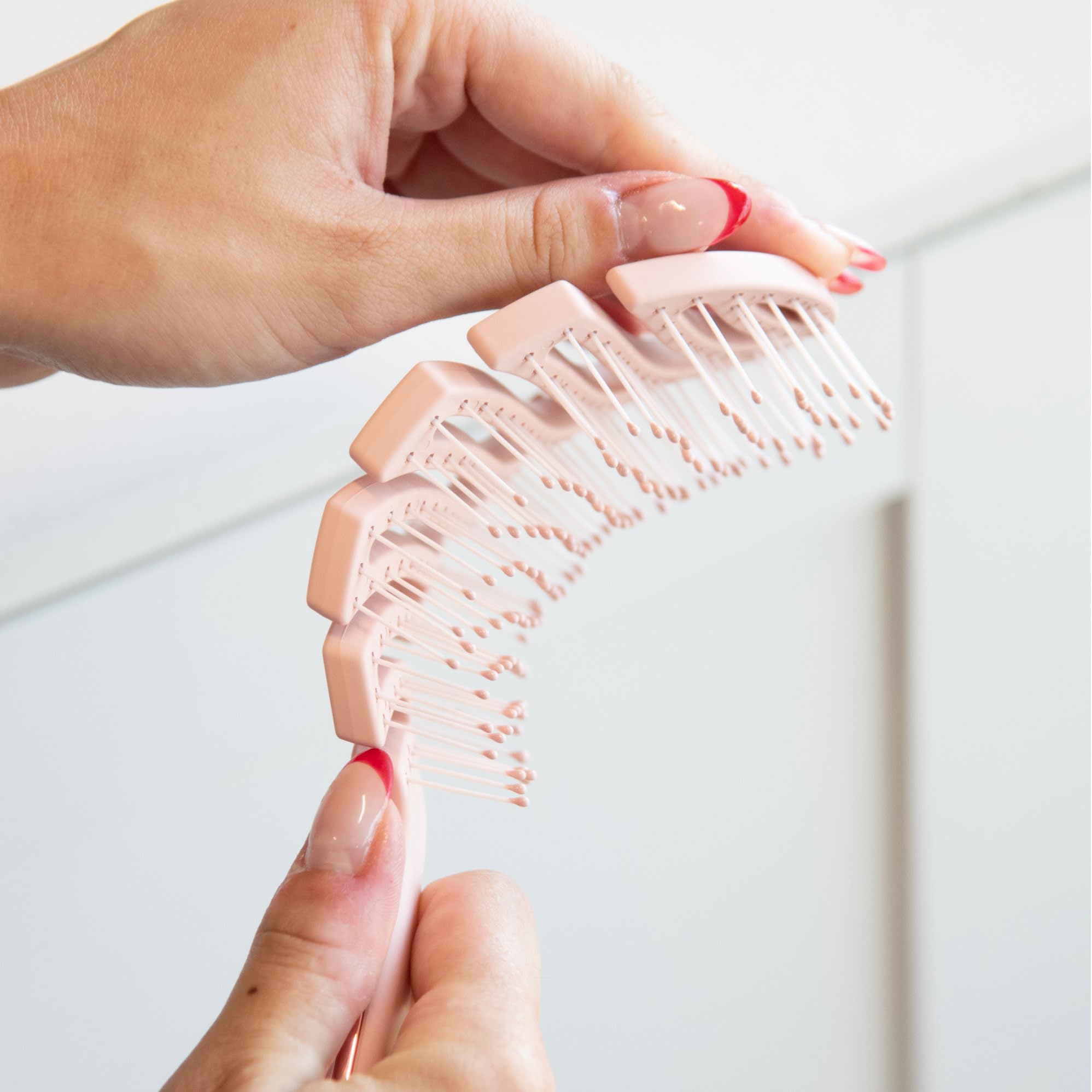 FRAMAR vented pink hair brush in hand for versatile styling and on-the-go use