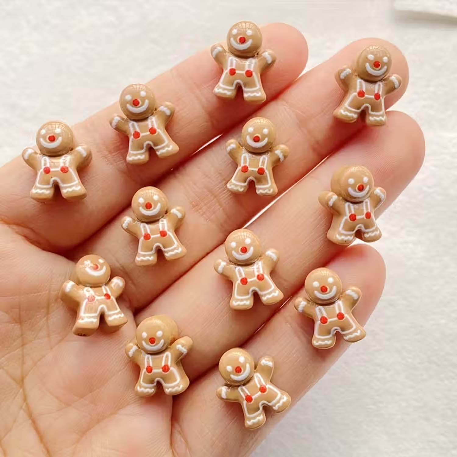 Gingerbread-man nail charms being applied with glue for easy home manicure
