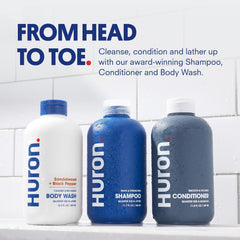 Huron Shower Kit conditioner bottle highlights nourishing care for dry, frizzy hair.