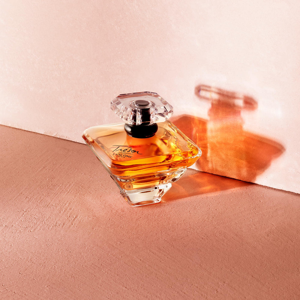 Lancôme Trésor frasco dorado con tapón de diamante, lujo visible.