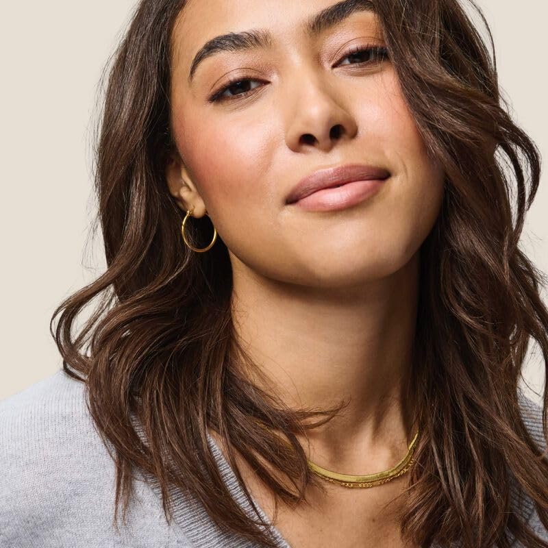 Living Proof No Frizz Instant De-Frizzer hand applying spray for between-wash refresh