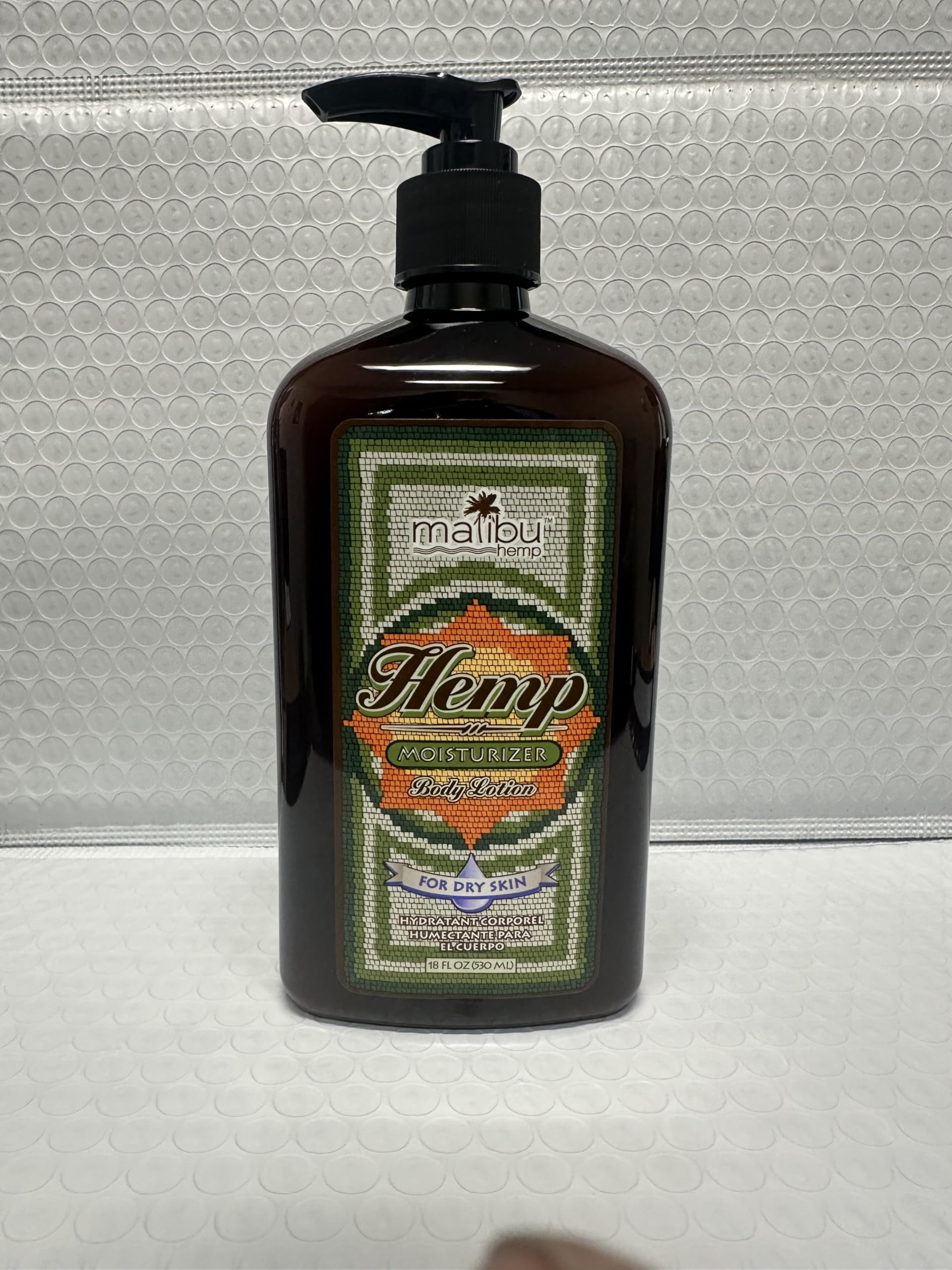 Malibu Tan Body Lotion beside towel implies daily bathroom routine