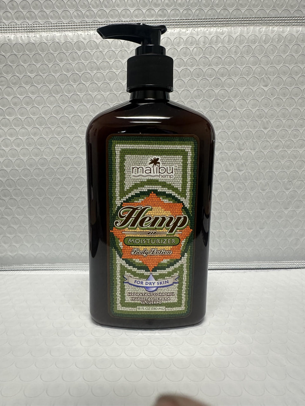 Malibu Tan Body Lotion beside towel implies daily bathroom routine