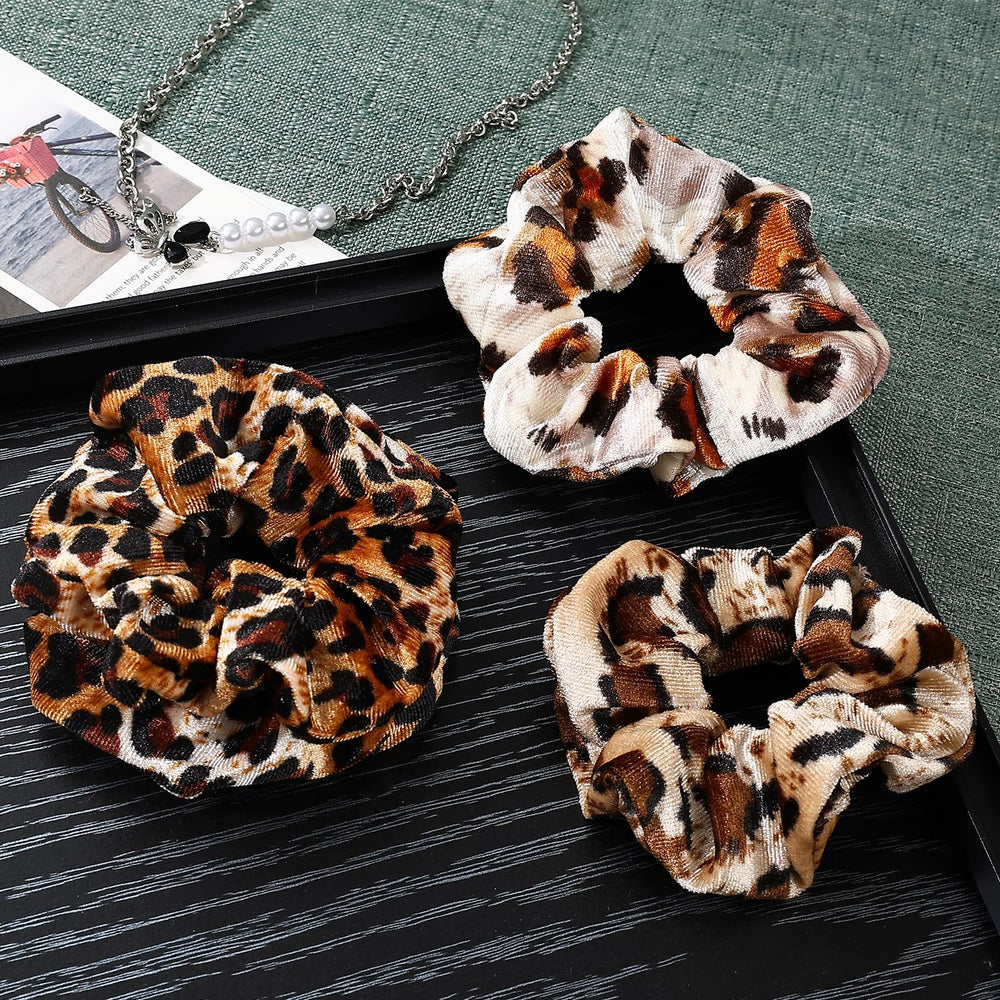 Mirlern leopard velvet scrunchies pair on hand, versatile fashion accessory for many looks.
