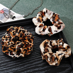 Mirlern leopard velvet scrunchies pair on hand, versatile fashion accessory for many looks.