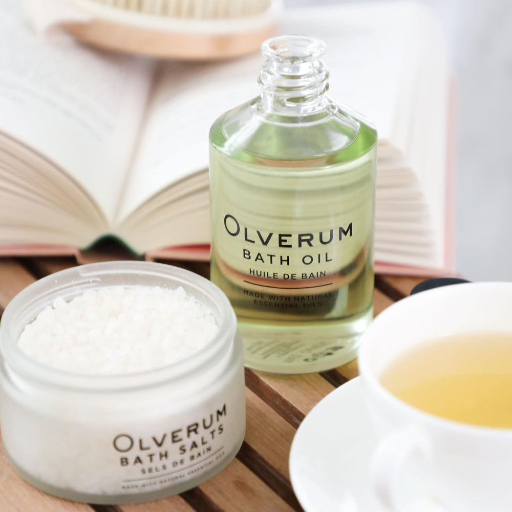 OLVERUM oil droplets glisten on skin, suggesting a self-care ritual.
