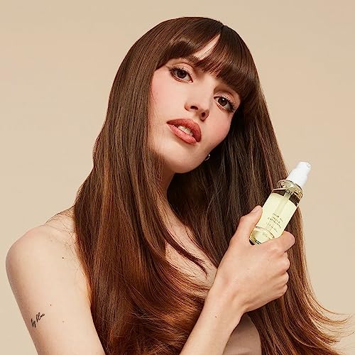 Hands applying OUAI Hair Oil for hydrating, heat-protective styling.