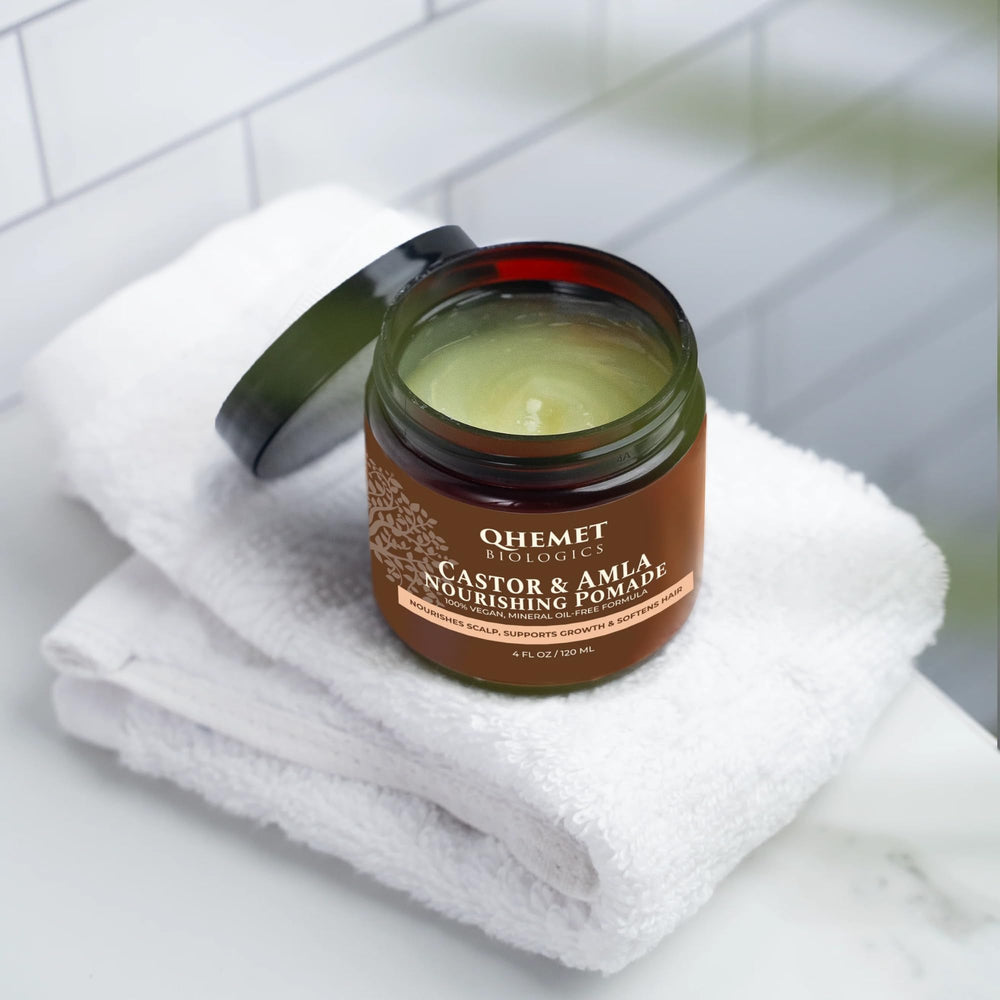 Creamy texture swirl of Qhemet Biologics Castor & Amla pomade ready to distribute