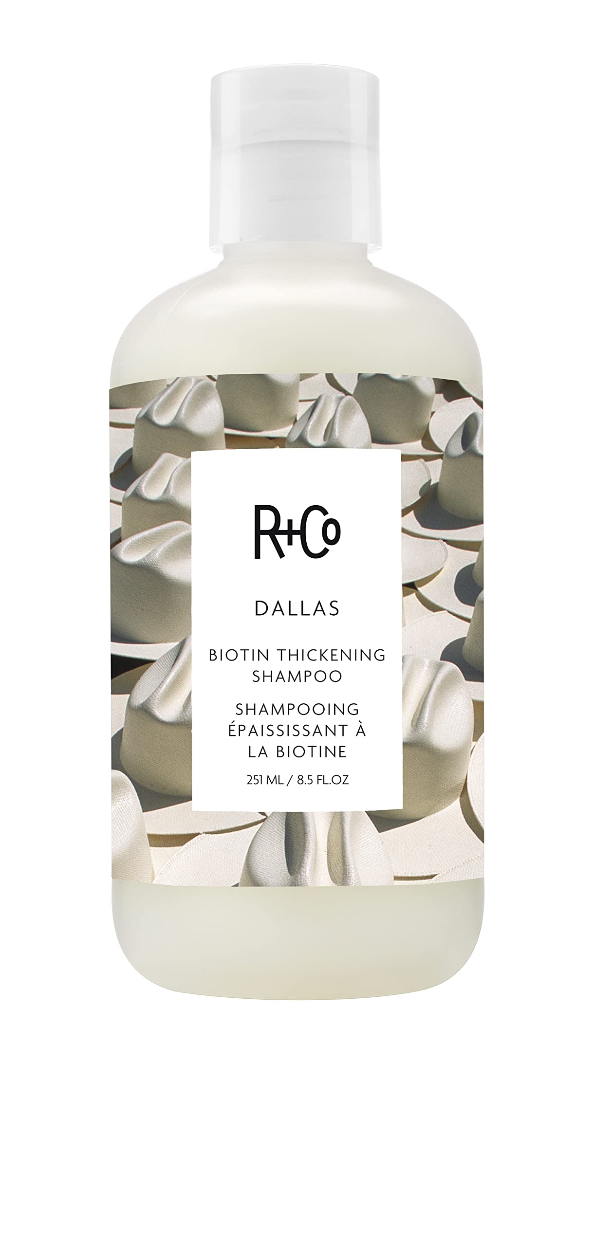 R+Co Dallas Thickening Shampoo bottle close-up highlights volumizing care for fine hair.