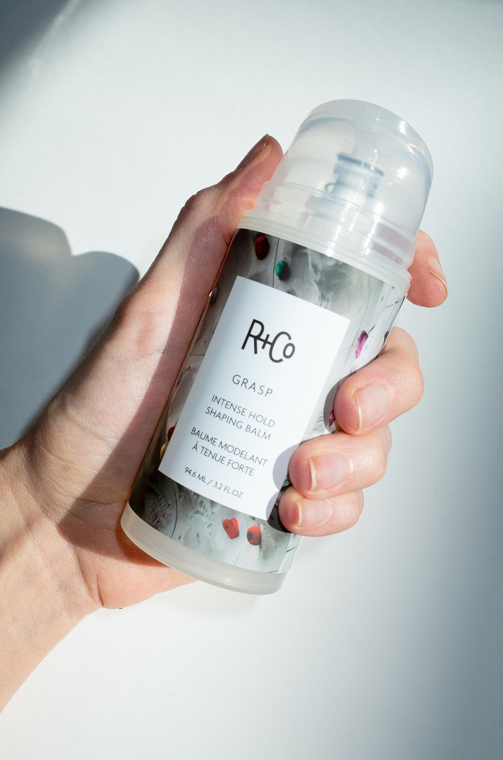 R+Co Grasp balm frizz control for smooth, controlled styling on humid days.
