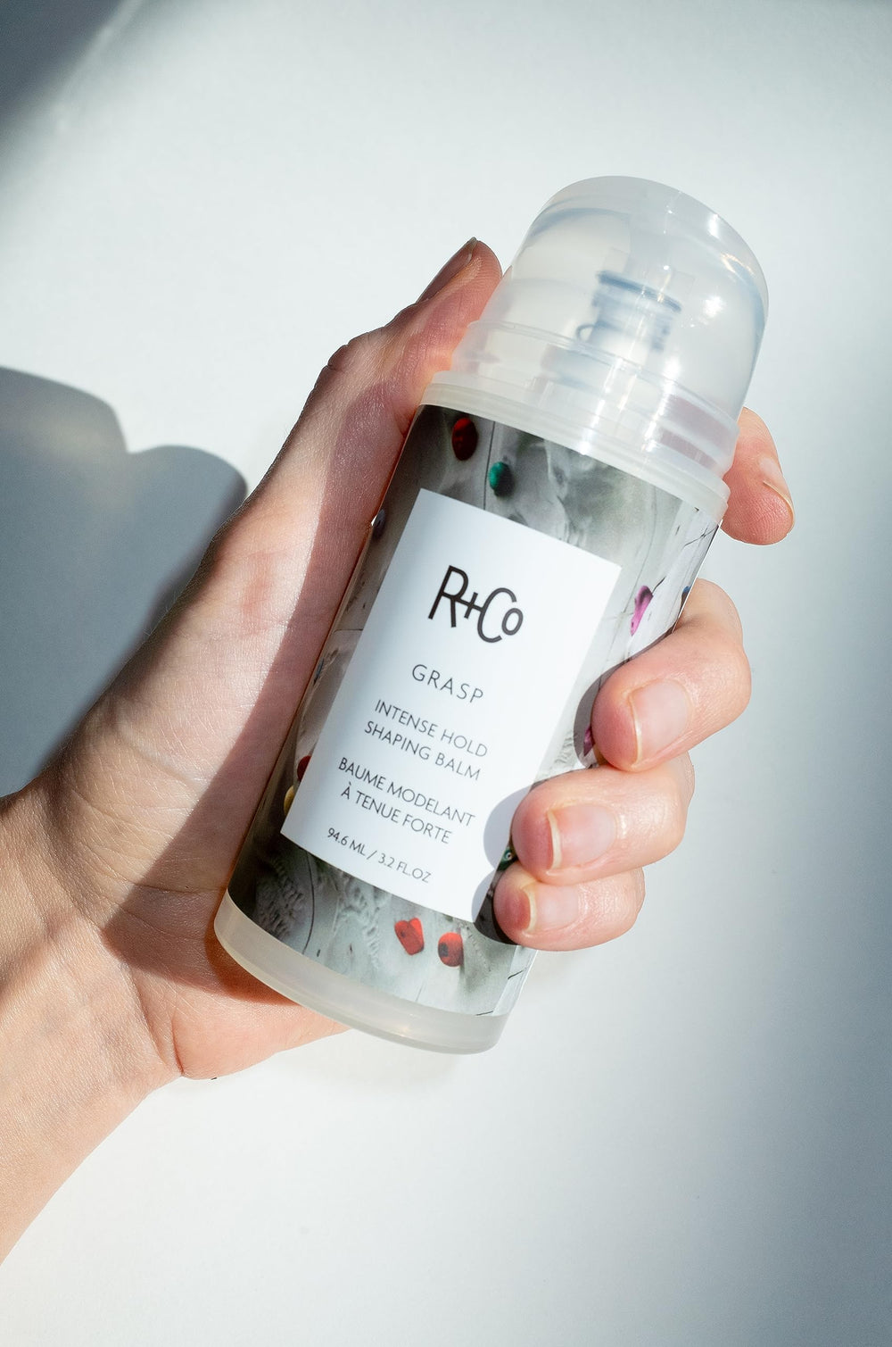 R+Co Grasp balm frizz control for smooth, controlled styling on humid days.