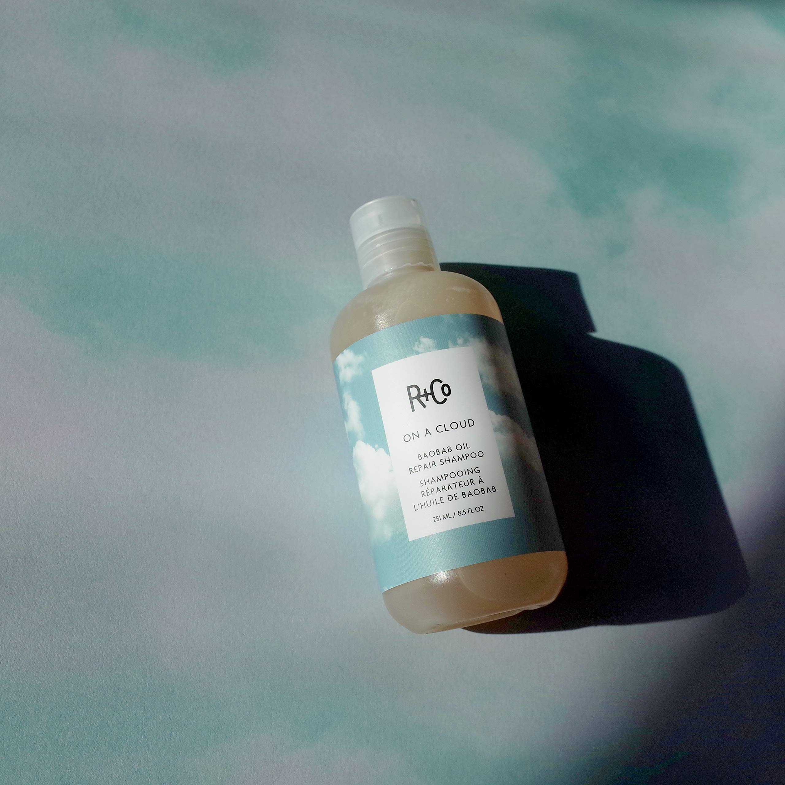 Pour shot of R+Co On A Cloud Baobab Repair Shampoo.