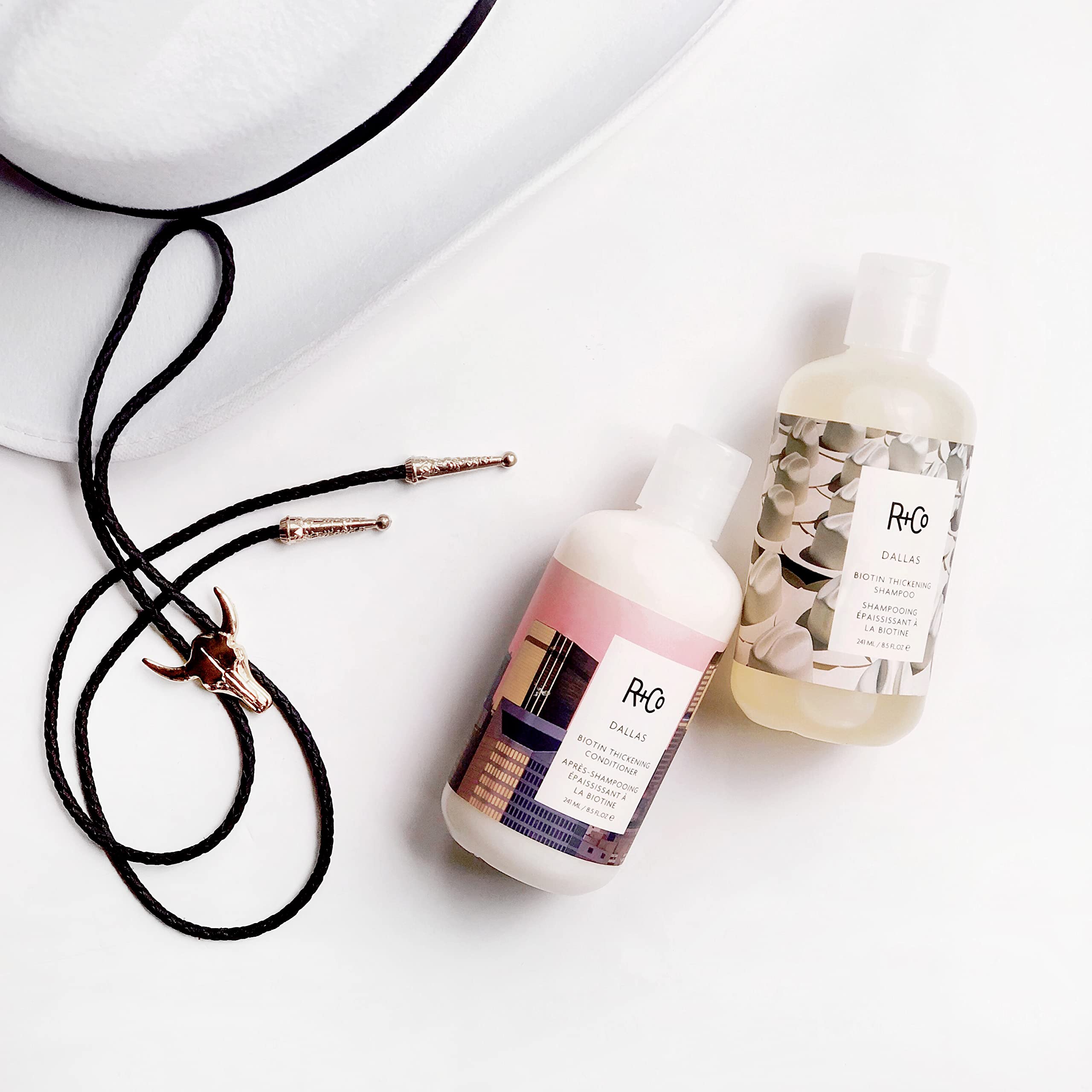 R+Co Dallas Thickening Shampoo amber bottle displayed on shelf.