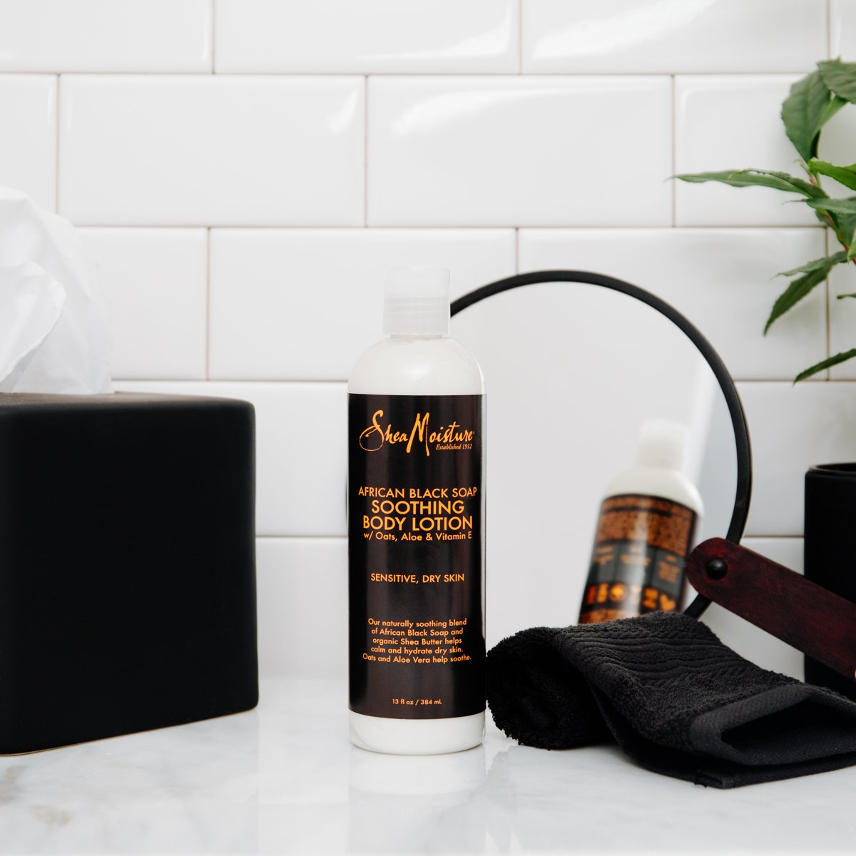 Hands applying SheaMoisture lotion to damp skin for better moisture retention.