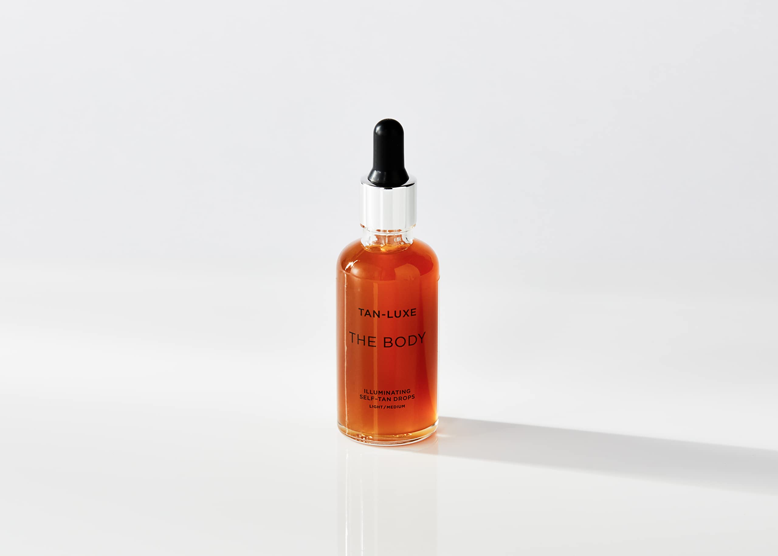 Tan-Luxe The Body Illuminating Drops dropper in use for customizable tan shade