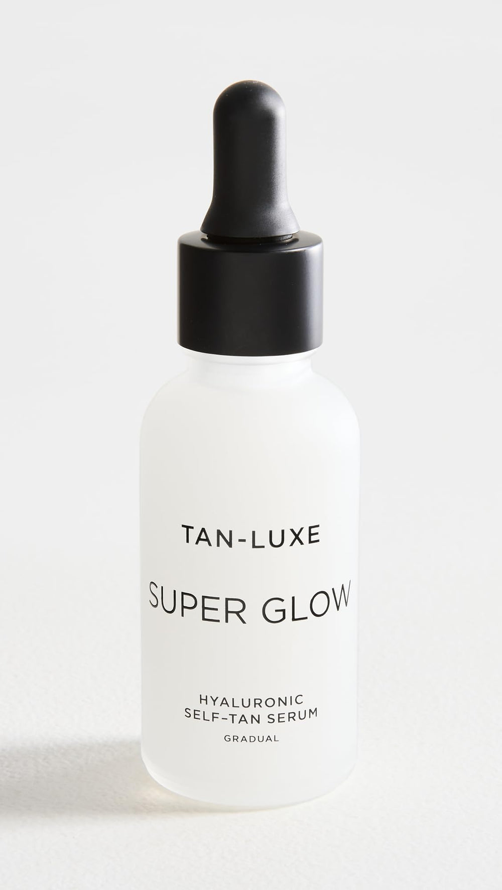 Close-up of TAN-LUXE Super Glow dropper applying serum for daily hydration and glow.