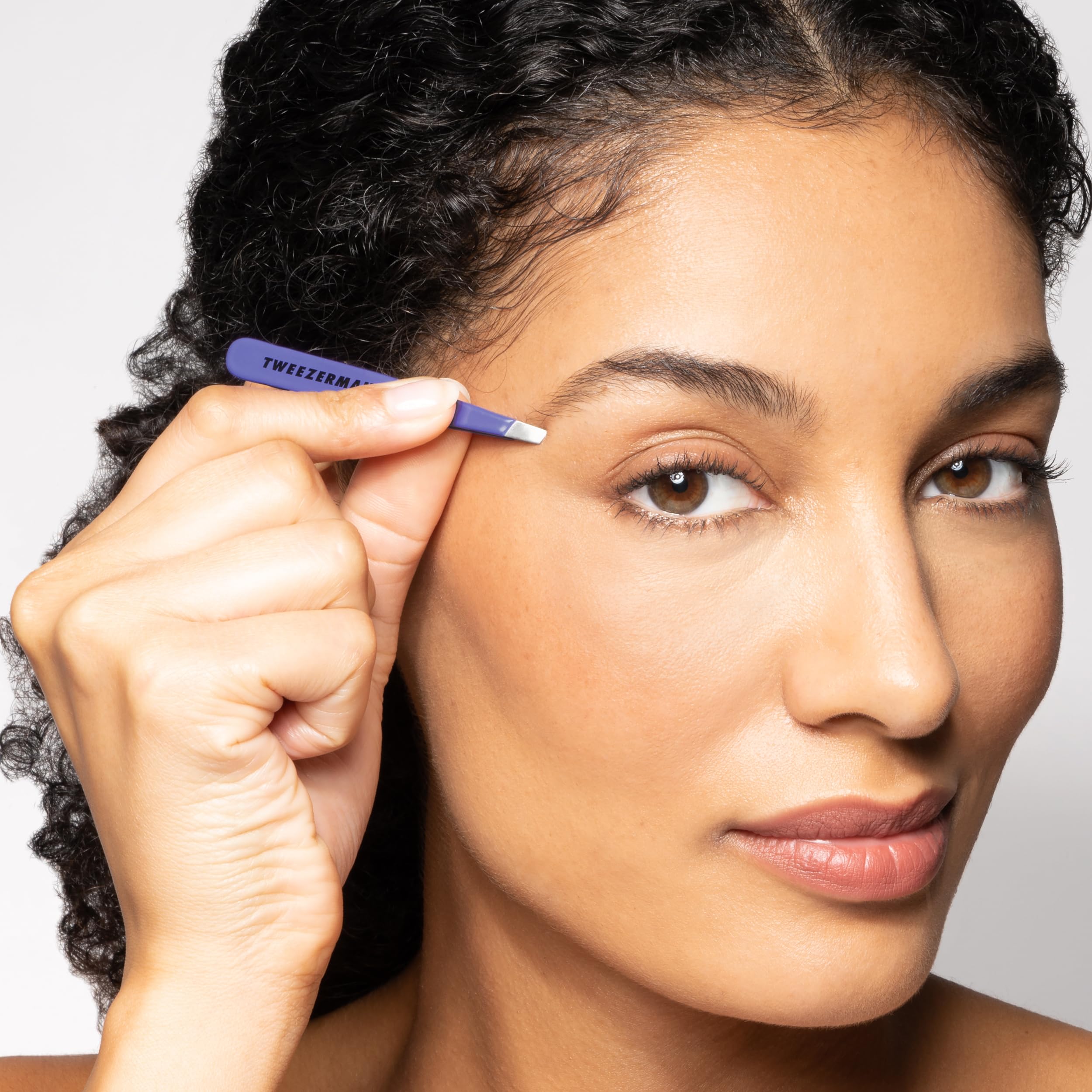 Tweezerman Mini Slant Travel Tweezers Blooming Lilac shown with ergonomic grip for control.