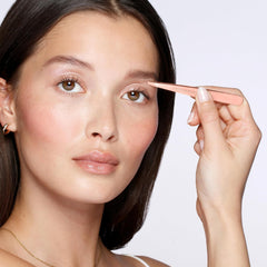 Angled 25-degree tip on Tweezerman rose-gold tweezer for controlled plucking.