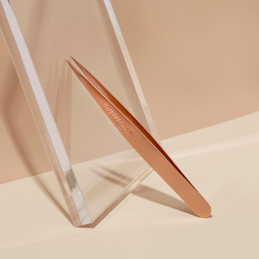 Tweezerman rose-gold tweezers used for brow shaping and fine-hair removal.