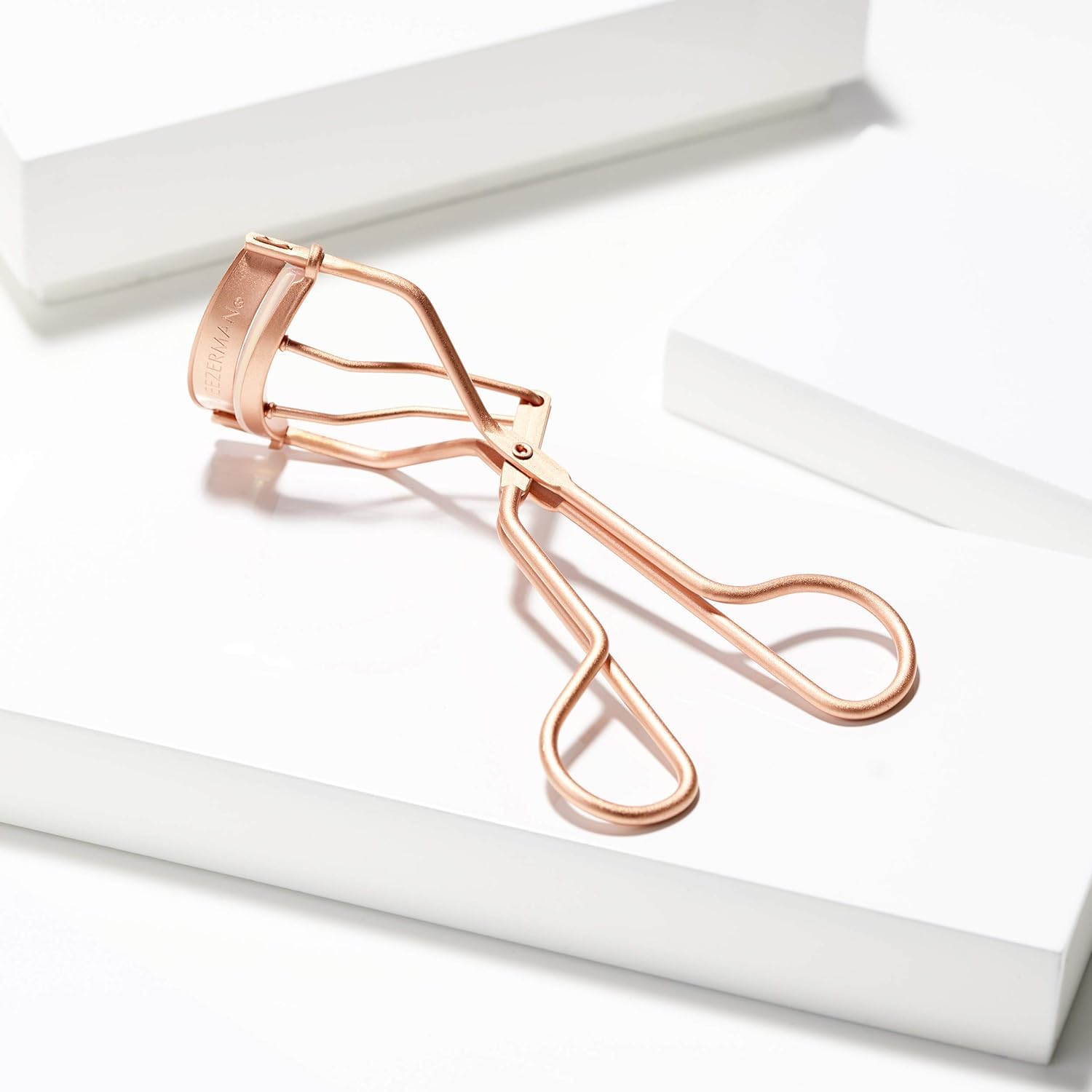 Tweezerman Rose Gold Eyelash Curler before-and-after showing lifted lashes.