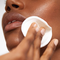 Versed Weekend Glow cotton pad saturated for gentle facial toner application.