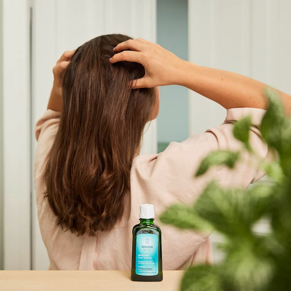 Weleda Rosemary Conditioning Hair Oil bottle beside glossy hair result